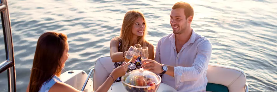 Groupe d'amis sur un bateau buvant du vin au coucher du soleil