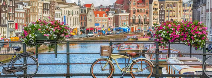 Les canaux d'Amsterdam, bordés de maison aux façades colorées et aux ponts ornés de bicyclettes et compositions florales