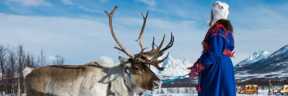 Une femme en tenue traditionnelle aux côtés d'un rêne en Norvège du Nord, Laponie de Tromso