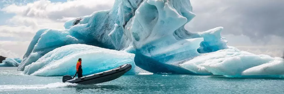 Homme naviguant en zodiac à travers les icebergs du Groenland