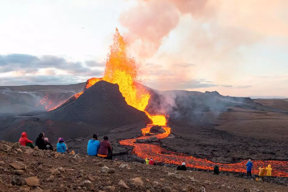 Petit groupe de personnes assistant à une éruption volcanique